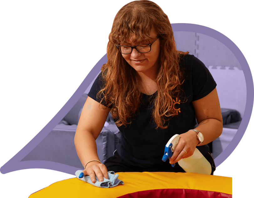 A young person cleans soft play equipment, wearing the uniform of Radiant Cleaners, a cleaning social enterprise.