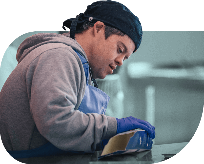 A baker from social enterprise Step and Stone assembles packaging for flatbreads in a commercial kitchen.