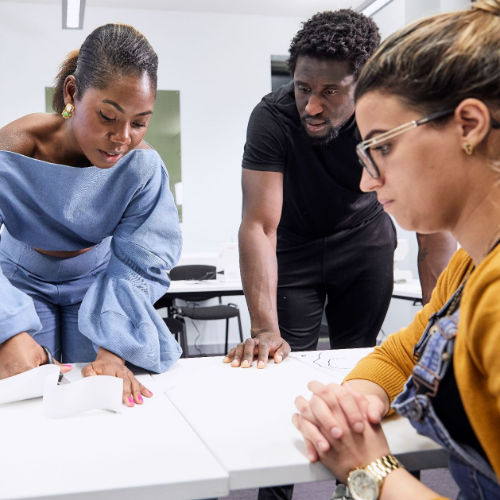 A child in a blue raincoat holds a mini trowel in a community garden.